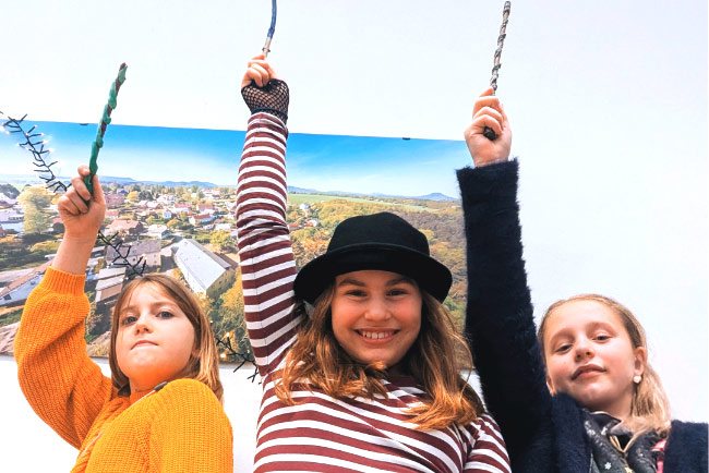 3 Mädchen halten Zauberstäbe hoch