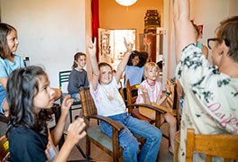 Kinder sitzen zusammen und lernen Englisch im Feriencamp. 