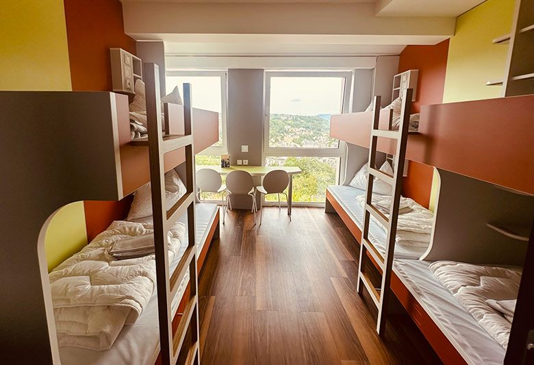 Mehrbettzimmer der Jugendherberge Idar-Oberstein mit roten Stockbetten und einem Tisch mit St�hlen. 