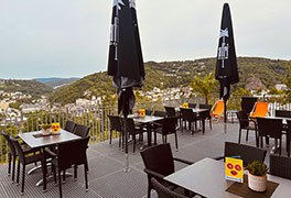 Großzügige Terrasse der Jugendherberge Idar-Oberstein mit modernen Möbeln und einem weiten Blick über die Landschaft. 