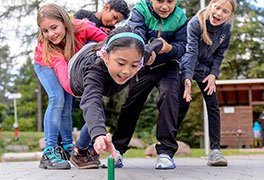 Teamübung einer Schulklasse. Kinder versuchen einen Stein zu erreichen.