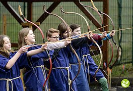 Schüler sind als Römer verkleidet und schießen mit einem Bogen. 