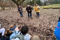 Eulenwanderung. Schüler sitzen im Kreis und hören den Falknern mit Eulen auf dem Arm zu. 